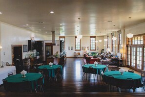 A spacious room with multiple tables and chairs, a bar area, and large windows allowing natural light. - HISTORIC 1945 SCHOOLHOUSE. 4700 sq. ft. of luxury five minutes from Lake Fork. (Como)