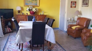 A dining area with a table set for four, a television, and a bookshelf. - Accommodations in St. Bonnet Tronçais (Saint-Bonnet-Tronçais)