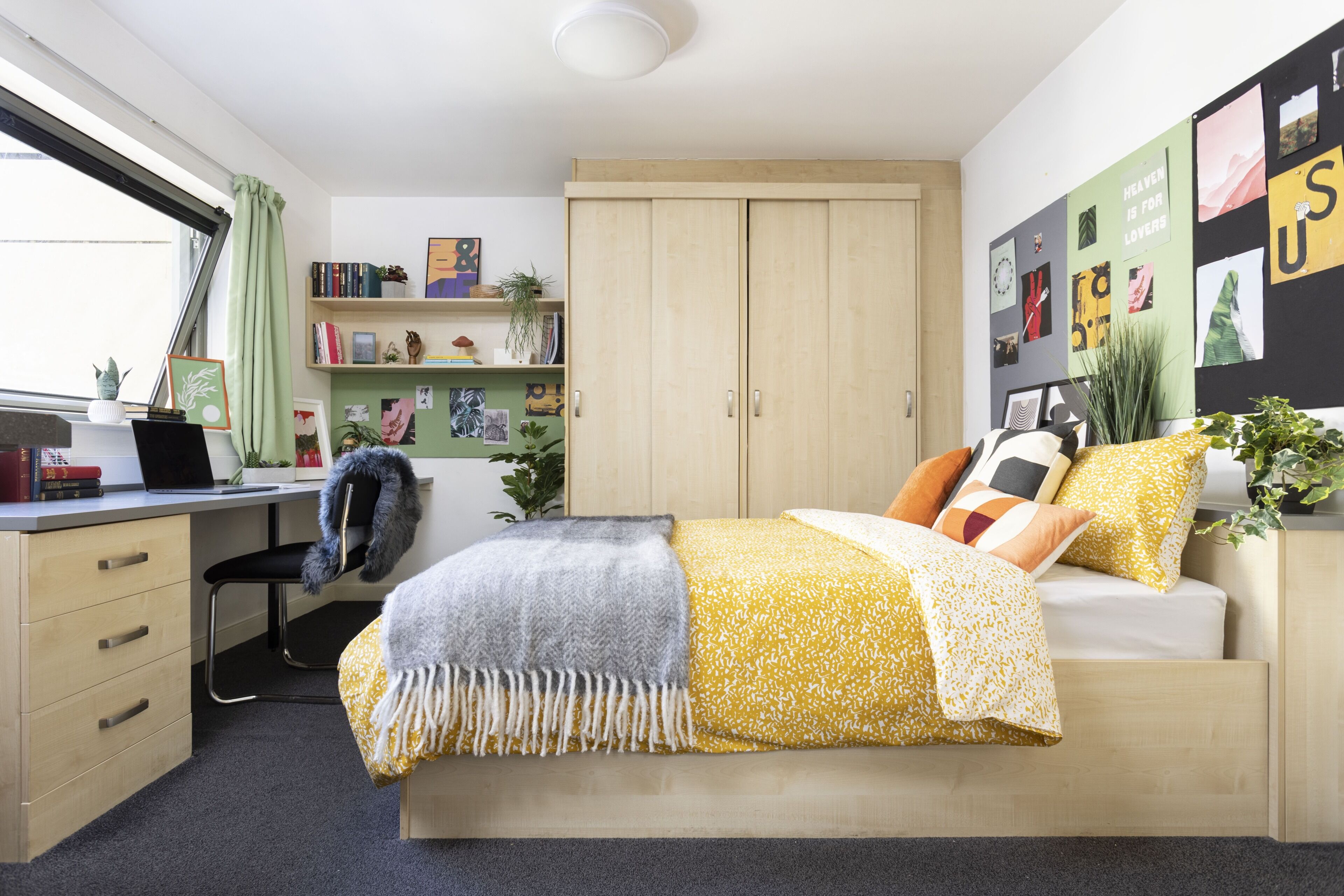 A bedroom with a bed, desk, chair, and wardrobe.