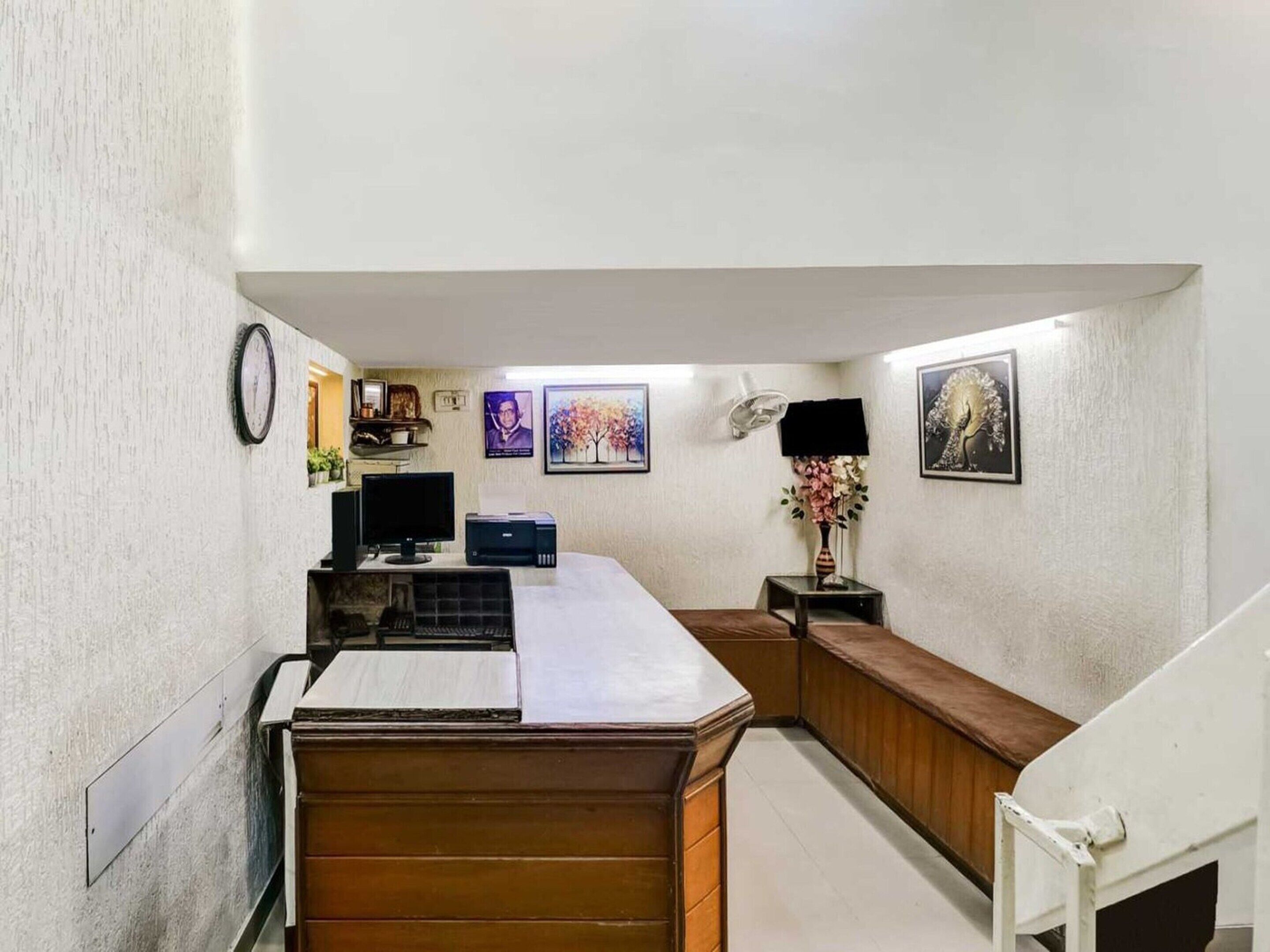 A hotel room with a desk, computer, and a small seating area.