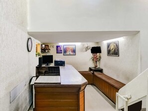 Ein Hotelzimmer mit Schreibtisch, Computer und einer kleinen Sitzecke.