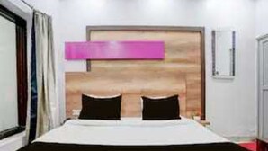 A hotel room with a bed, a wooden headboard, a window, and a door. - Classic Sindhi Camp Paul Avenue (Jaipur)