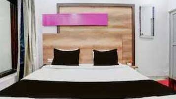 A hotel room with a bed, a wooden headboard, a window, and a door.
