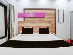 Ein Hotelzimmer mit Bett, Holz-Kopfteil, Fenster und Tür.