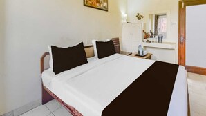 A hotel room with a bed, a nightstand, a mirror, a wardrobe, and a painting on the wall. - Classic Sindhi Camp Paul Avenue (Jaipur)
