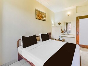 Ein Hotelzimmer mit einem Bett, einem Nachttisch, einem Spiegel, einem Kleiderschrank und einem Bild an der Wand.