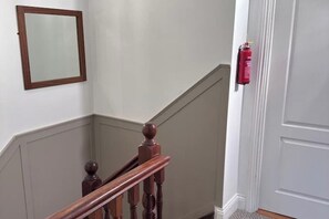 A staircase with wooden balusters, a white door, and a fire extinguisher mounted on the wall. - The Sailor's Galley (Aghada)