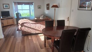 Un'area pranzo con un tavolo rotondo e sedie, un divano, una televisione e una finestra con vista.