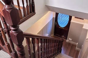 A wooden staircase with a handrail, a carpeted landing, and a door with a window.