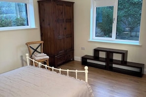 Un dormitorio con cama, un armario de madera, una silla y una mesita.