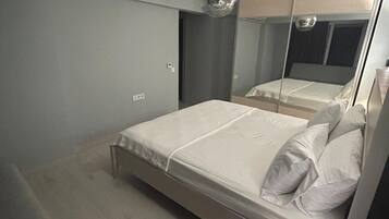 Um quarto moderno com cama, mesa de cabeceira, espelho e luminária no teto.
