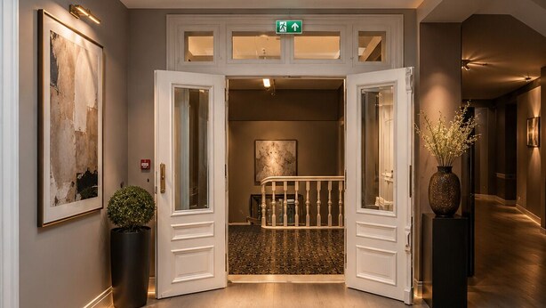 Een hotel lobby met een dakraam, een glazen vloer, een trap en een lijstwerk kunstwerk.