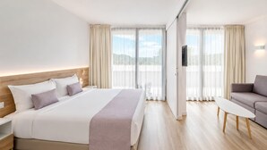 A hotel room with a bed, a sofa, a TV, and a view of the outdoors. - Romantic Coastal Apartment Hideaway (Castell-Platja d'Aro)