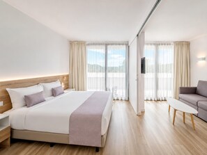 A hotel room with a bed, a sofa, a TV, and a view of the outdoors. - Romantic Coastal Apartment Hideaway (Castell-Platja d'Aro)