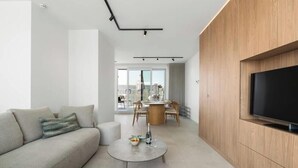 Ein modernes Wohnzimmer mit einer Couch, einem Couchtisch und einem an einer Holzwand montierten Flachbildfernseher.