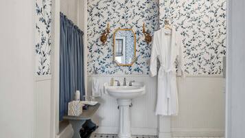 A bathroom with a white sink, mirror, and blue floral wallpaper.