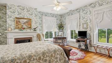 A bedroom with a bed, a television, a fireplace, and a window with a view.