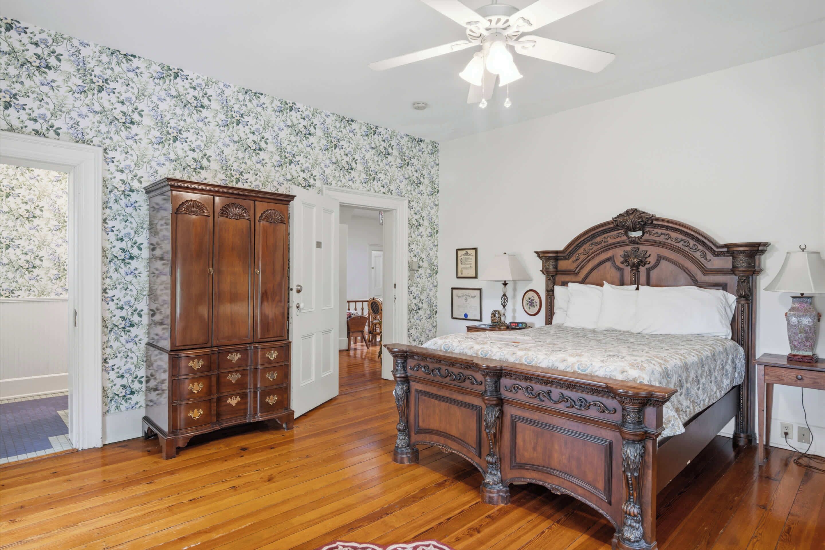 Een slaapkamer met een houten bed, een kledingkast en een plafondventilator.