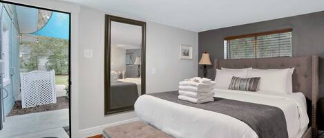 A bedroom with a bed, a bench, a mirror, and a window.
