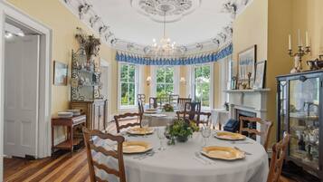 Une salle à manger avec une table ronde dressée pour six personnes, entourée de chaises en bois.