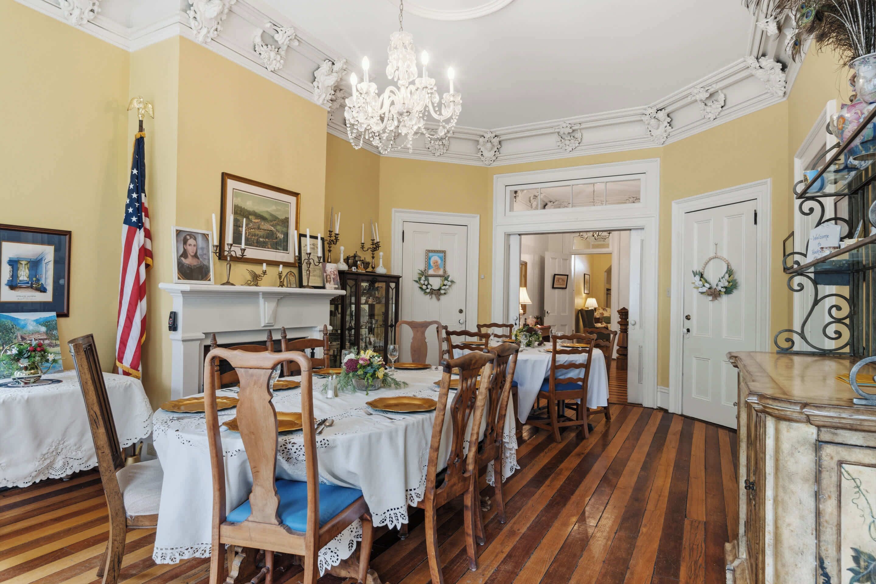 Une salle à manger avec un plancher en bois, des murs blancs et un lustre.