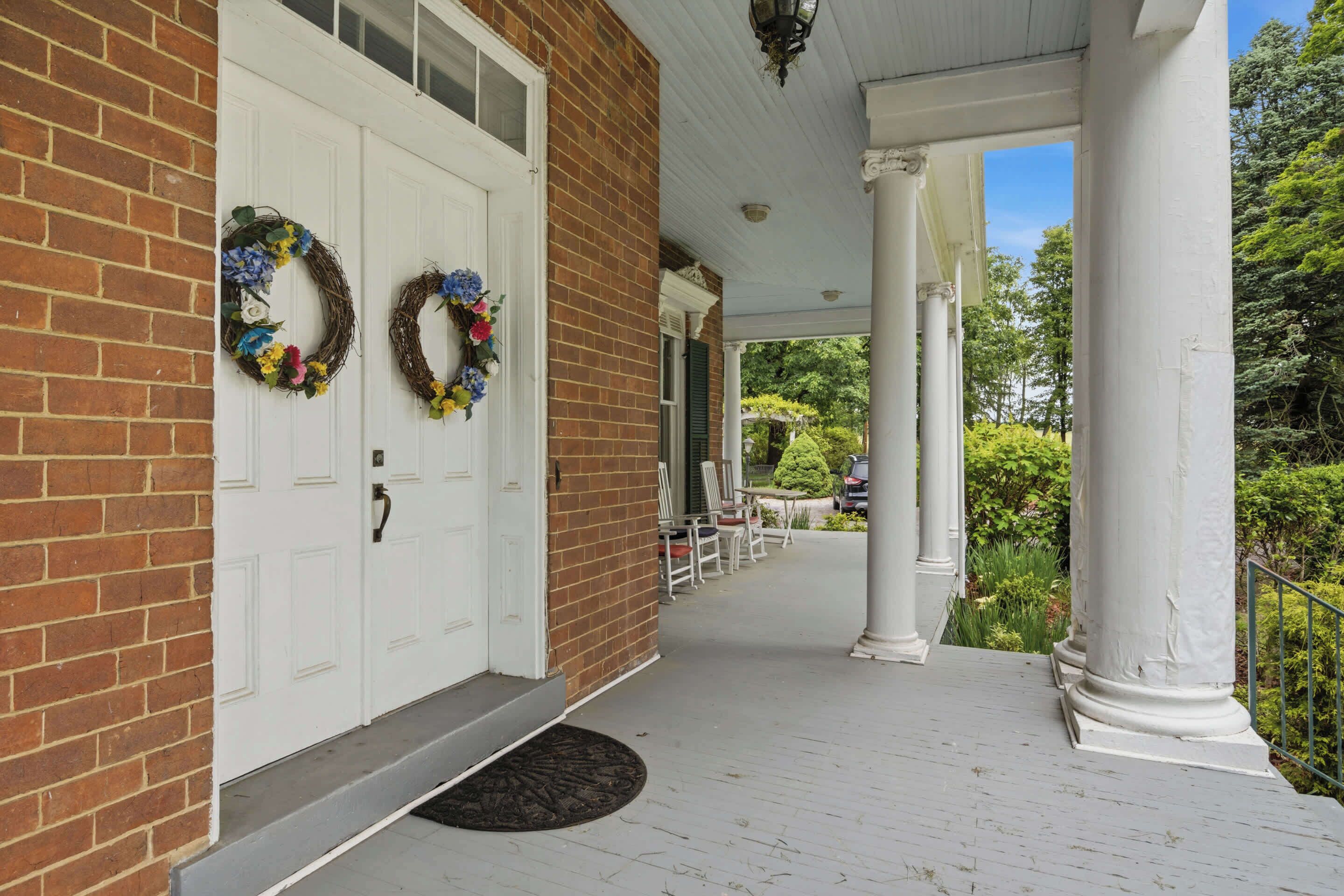 A brick building with white doors and a porch with columns.