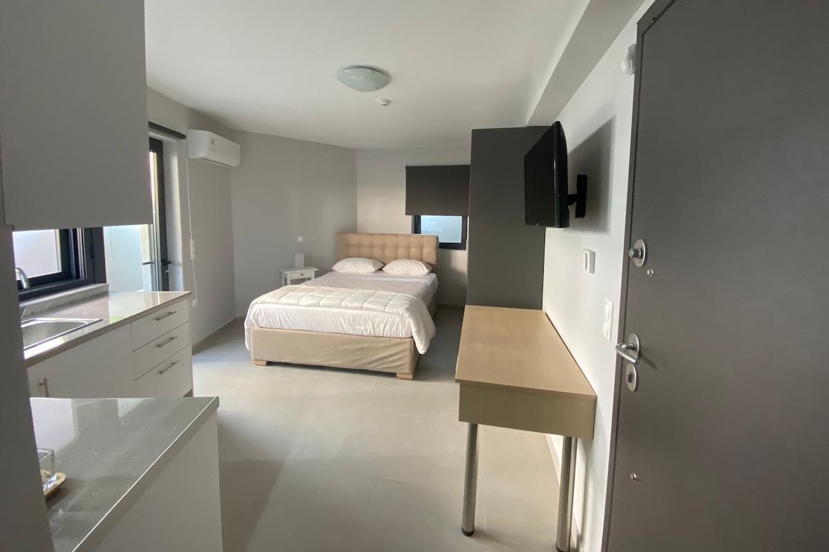 A modern bedroom with a bed, bedside tables, a desk, and a television.