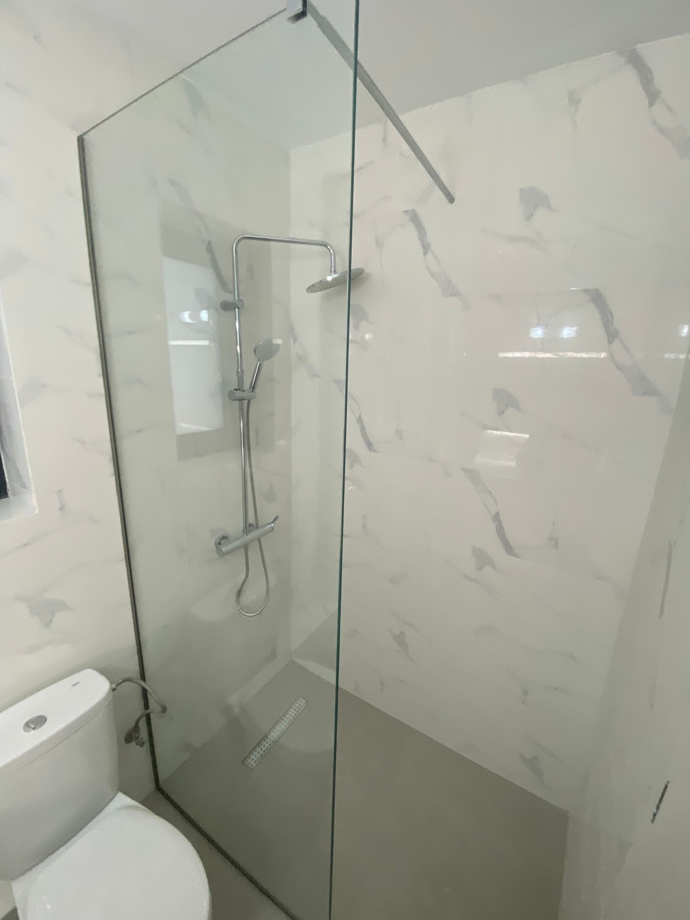 Una ducha envuelta en vidrio, con cabezal de ducha manual y grifo empotrado.