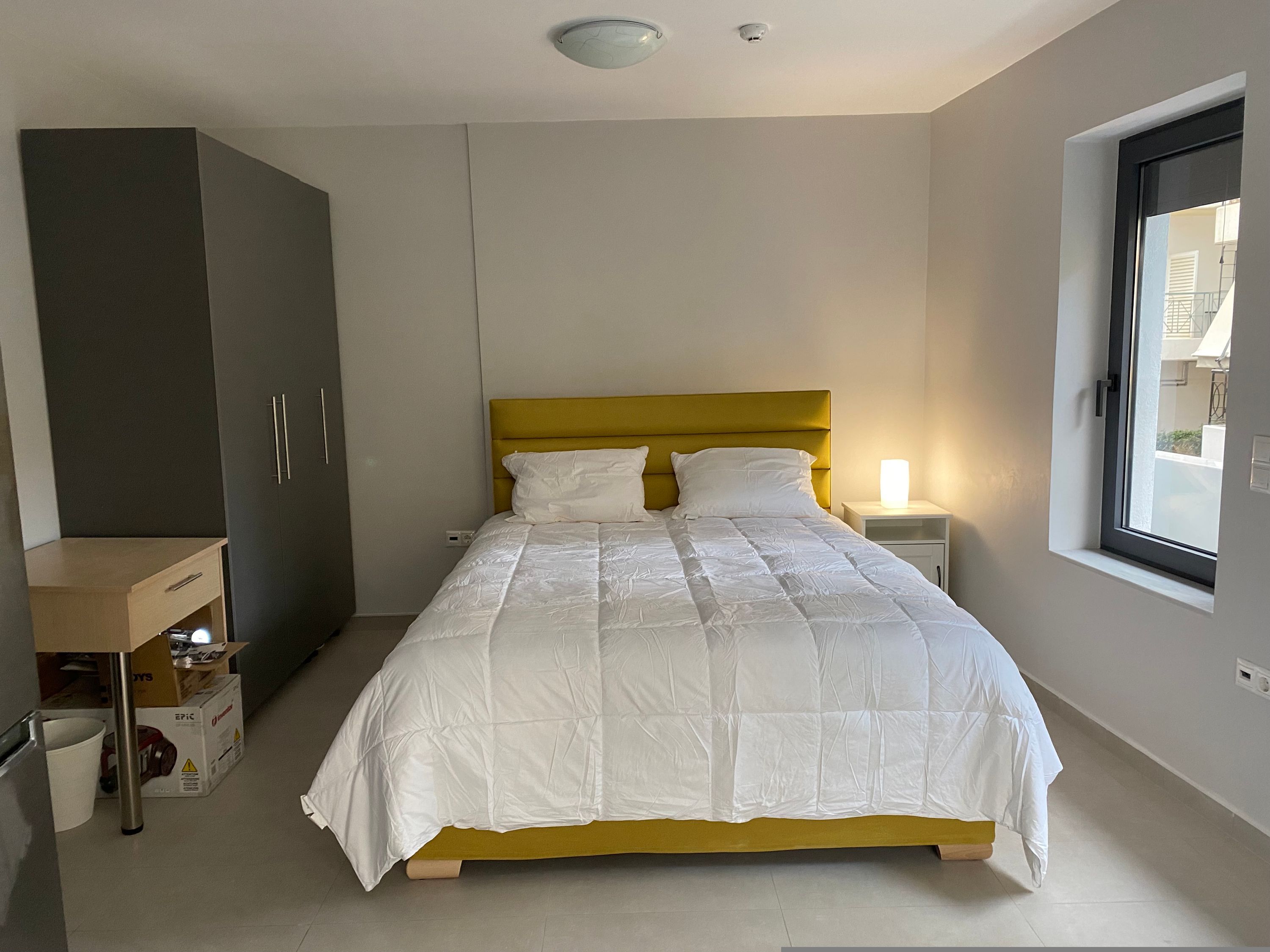 Une chambre à coucher avec un lit, une armoire, une table de chevet et une fenêtre.