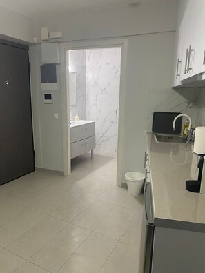 Une cuisine moderne équipée d’un four encastré, d’un évier et d’un plan de travail sur lequel se trouve une machine à café.