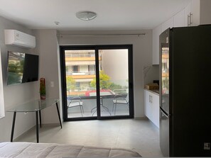 A modern apartment with a balcony, a TV mounted on the wall, a refrigerator, and a glass table. - Feels Like Home (Galatsi)