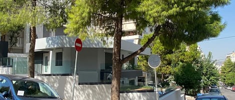 A street with parked cars, a no entry sign, and a tree.