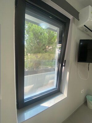 Quarto com janela de claraboia, televisão montada e lixeira.