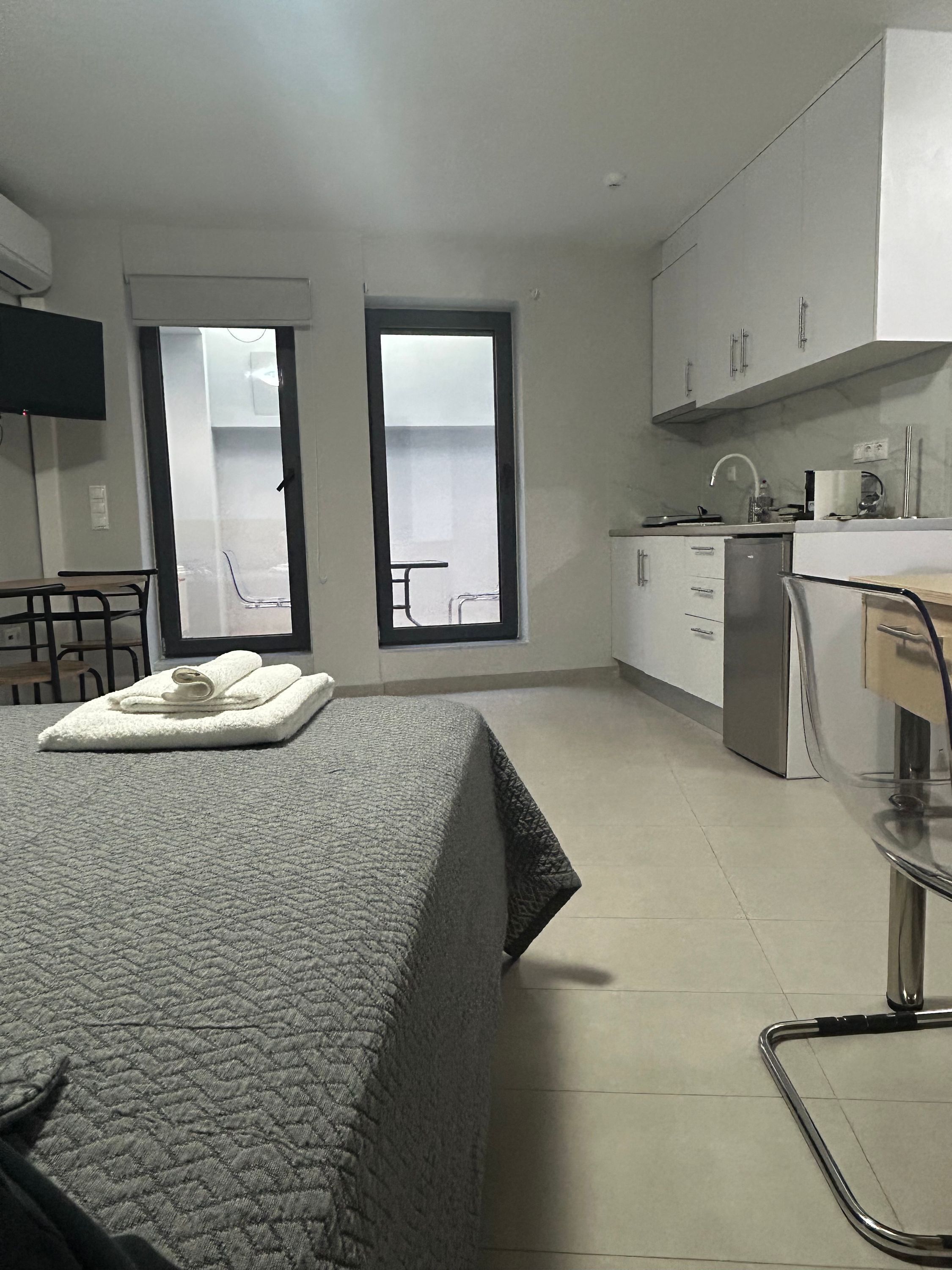 Habitació d'hotel amb llit, escriptori, cadira, petita cuina i bany.