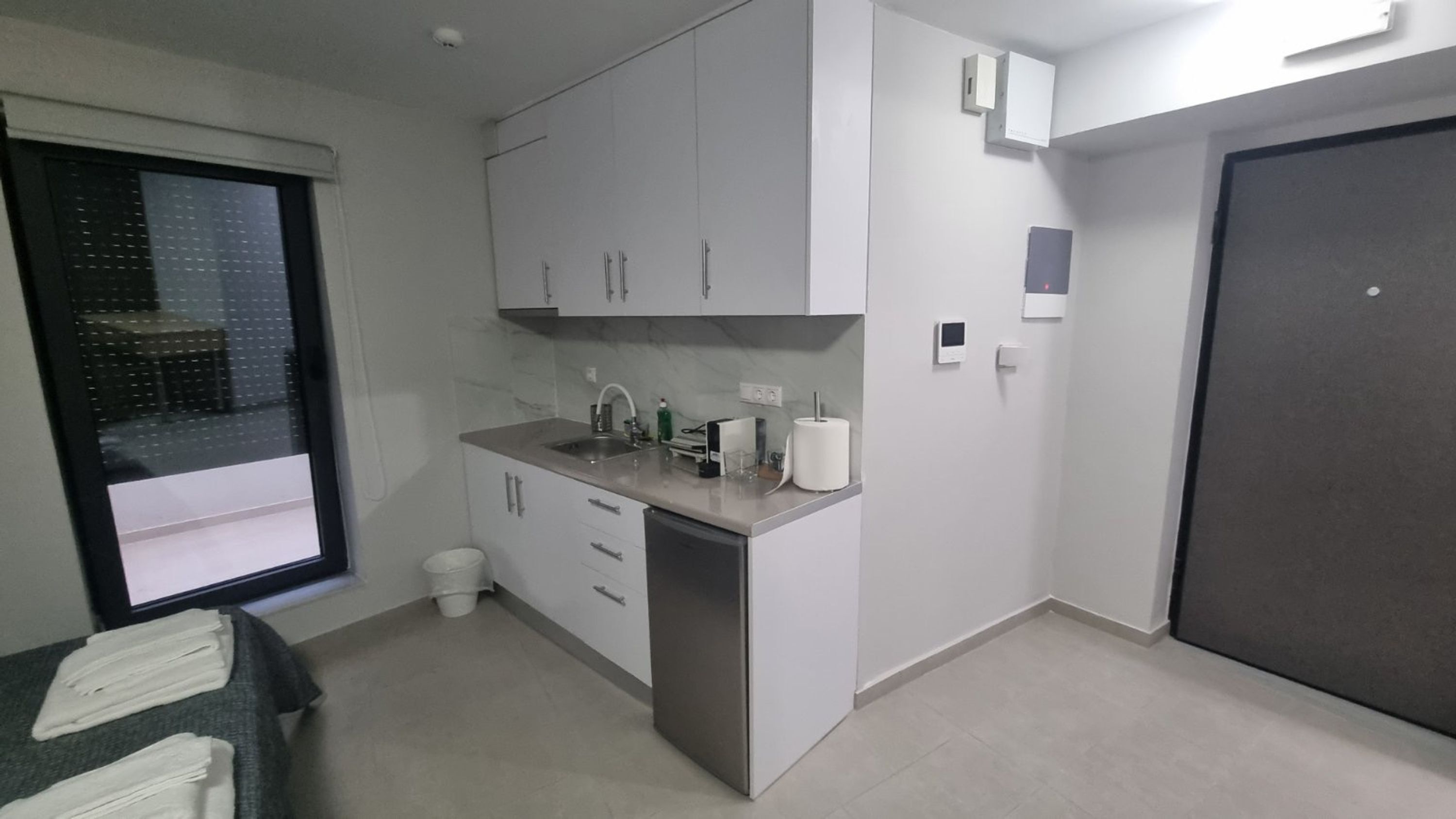 A compact kitchen with a window, a sink, cabinets, and a door.