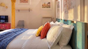 A bedroom with a wooden ceiling, a bed with white and orange pillows, a blue blanket, and a TV on a stand. - Studio Old Rome - Lungotevere (Rome)