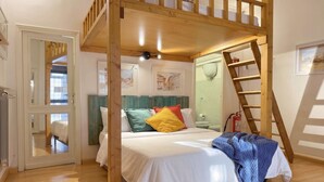 A bedroom with a bunk bed, a wooden ladder, a white bed with colorful pillows, a green headboard, and a framed picture on the wall. - Studio Old Rome - Lungotevere (Rome)