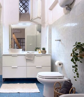 Ein Badezimmer mit Toilette, Waschbecken, Spiegel und einer kleinen Pflanze.