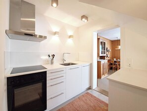 A modern kitchen with white cabinetry, a built-in oven, a stainless steel range hood, and a sink. - Chalet Willi-Parterre Appartement/Fewo, Dusche, WC, 2-Bettwohnung by Interhome (Arosa)