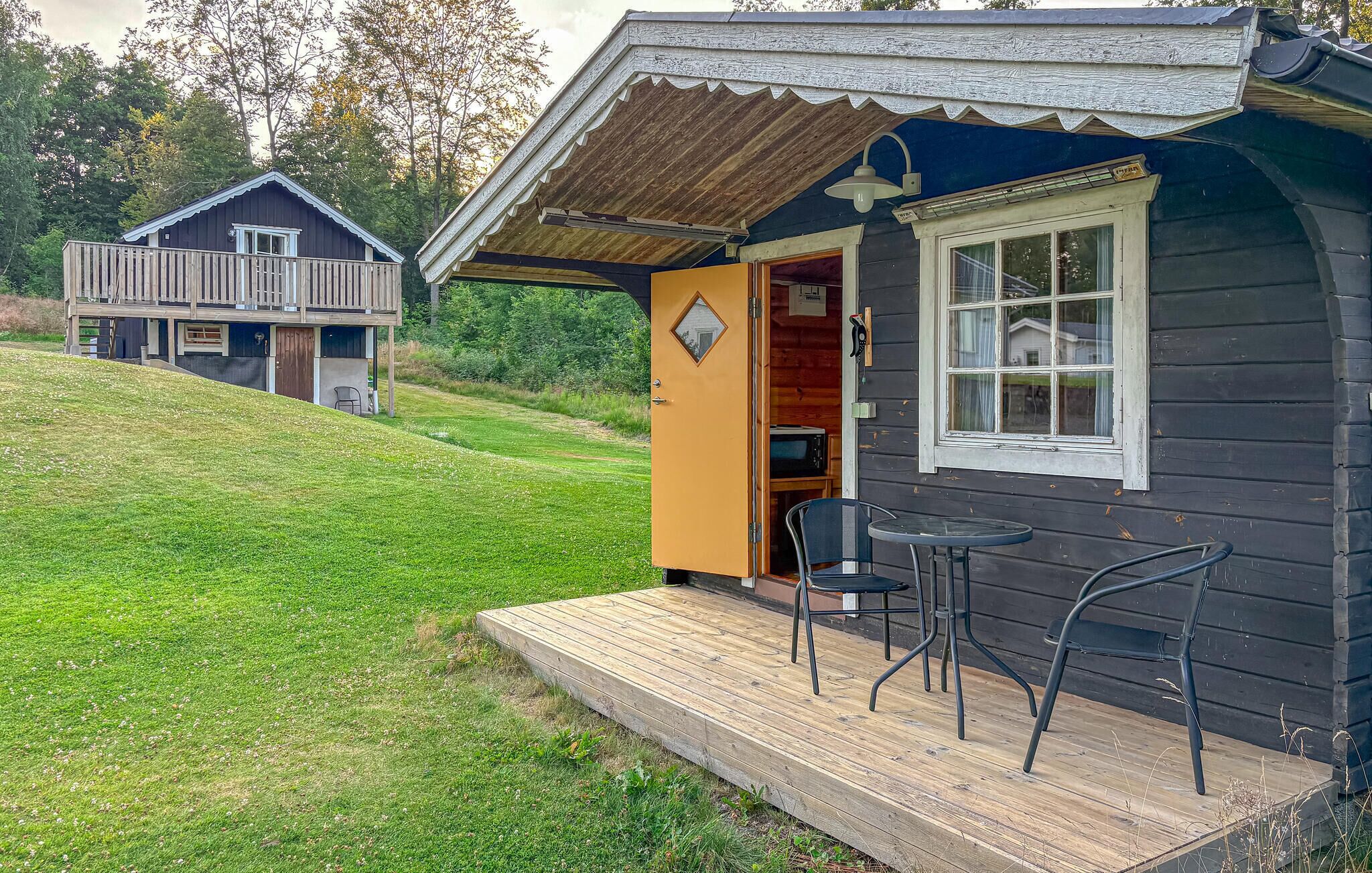 A cabin with a wooden deck, a dining area with chairs, and a small kitchen area.