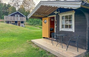 Eine Hütte mit einer Holzdiele, einem Essbereich mit Stühlen und einer kleinen Küchenzeile.