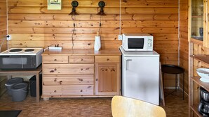 Ett kompakt kök med träskåp, en mikrovågsugn, en spis och ett handfat.