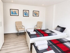 Habitación de hotel con cama, dos sillas, un mapa en la pared y suelo de madera.