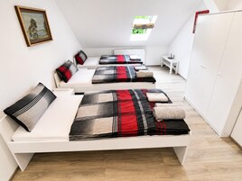 Una habitación con tres camas, un radiador, una ventana y un armario.