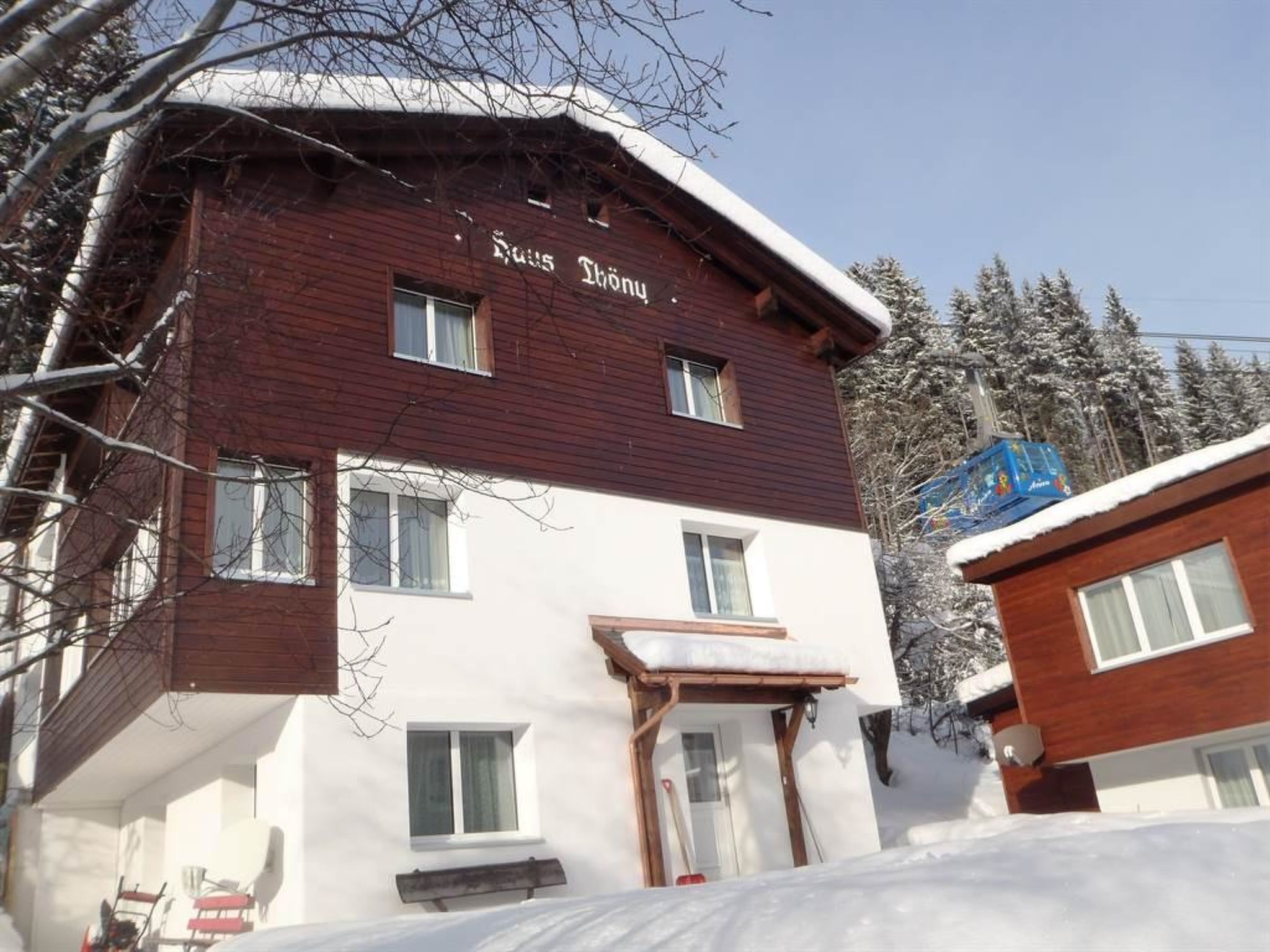 A two-story building with a wooden facade and a sign that reads 'Haus Thoni.'