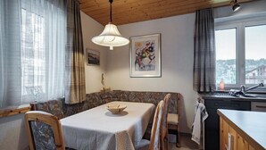 Un rincón comedor acogedor con una mesa, sillas, una lámpara colgante y un ventanal con vistas.