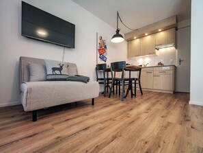 A modern apartment with a sofa, a dining table with chairs, a kitchen area, and a flat-screen TV mounted on the wall. - Paradies 212 Appartement/Fewo,  , 2-Bettwohnung 2-Bettwohnung by Interhome (Arosa)