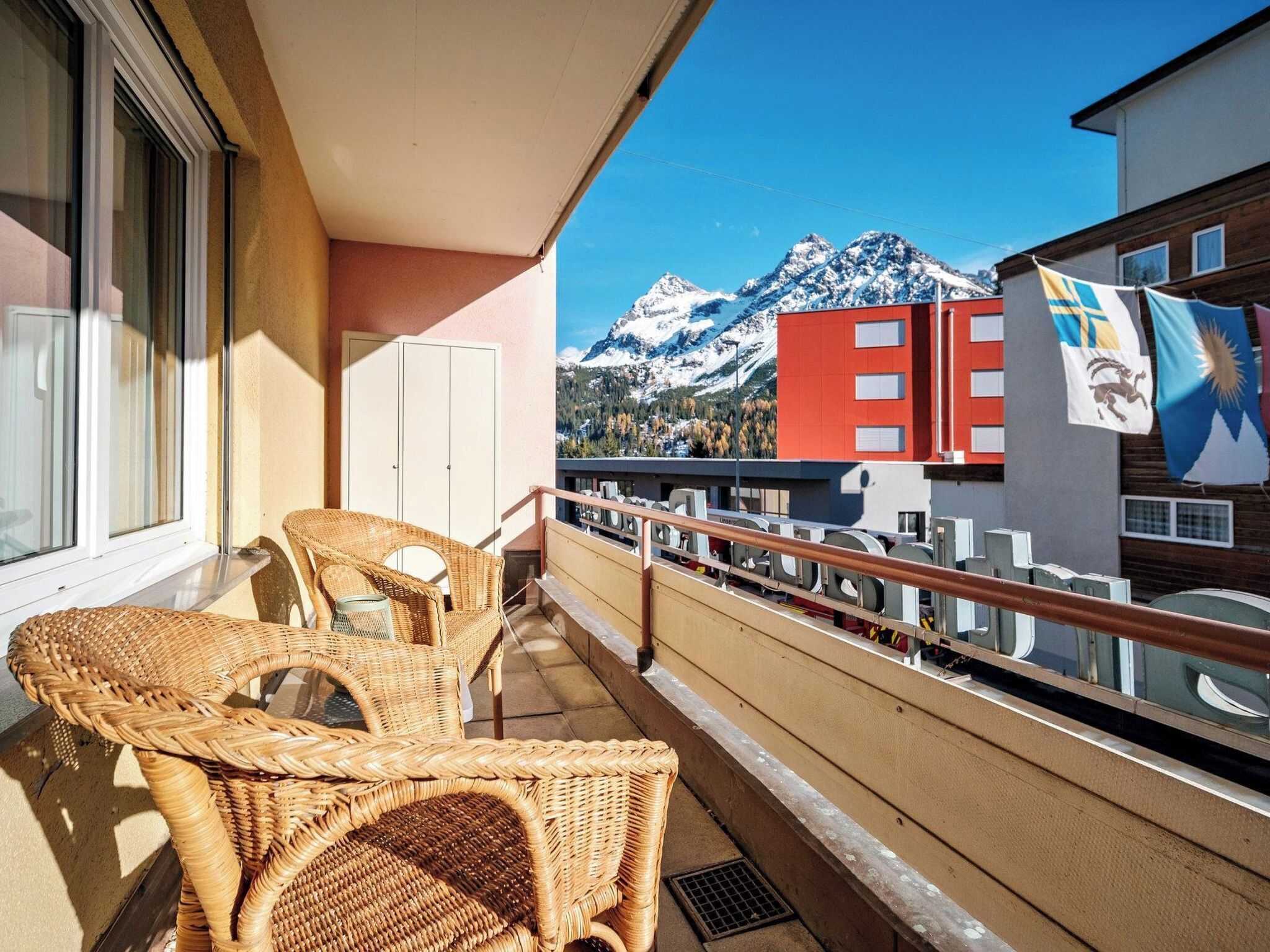 A balcony with wicker chairs, a window, and a view of a mountain.