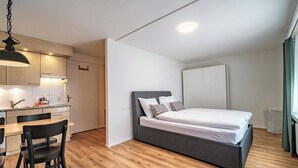 Un dormitorio pequeño con cama, escritorio y kitchenette.
