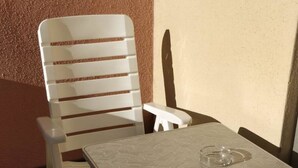 Een klein, afgesloten terras met een tafel en een stoel.
